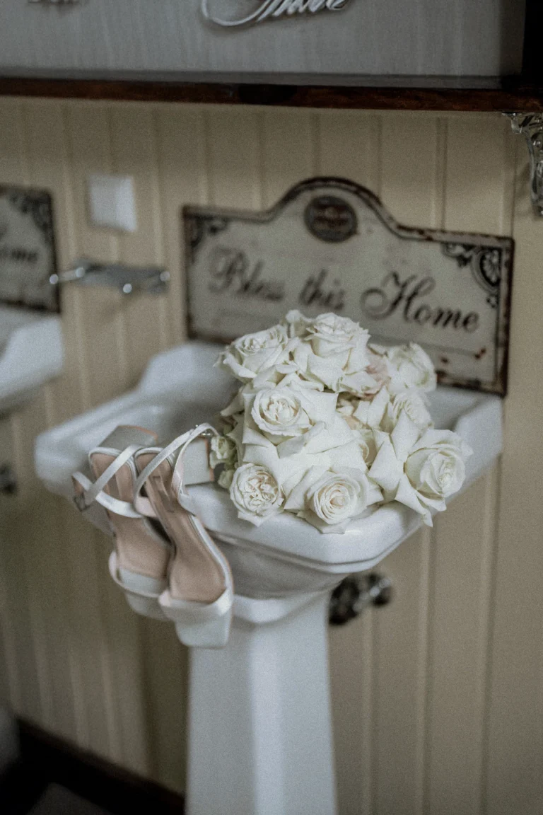 Bridal bouquet and wedding shoes placed on a vintage sink.