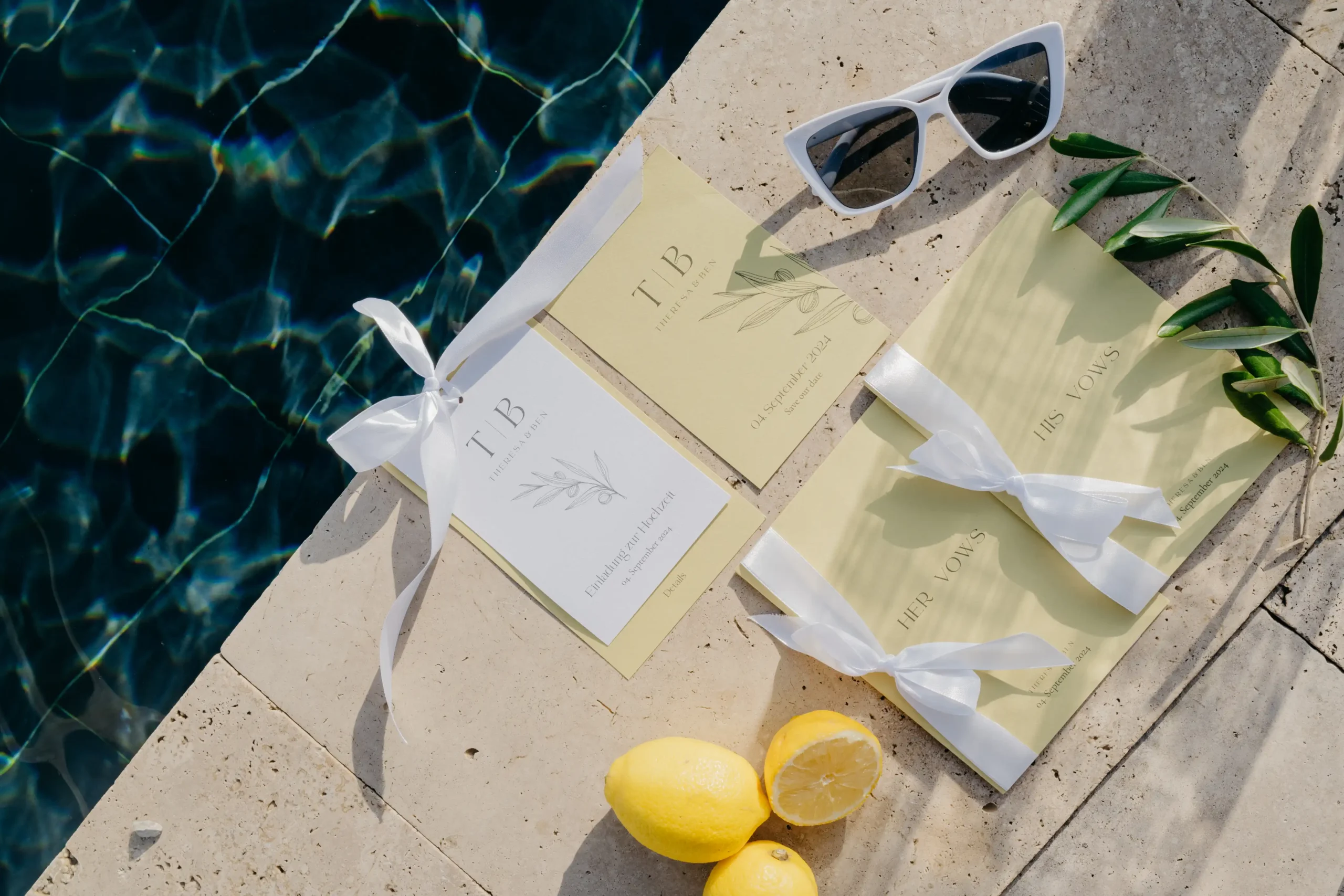 Wedding stationery and vow booklets with lemons and sunglasses by the poolside.