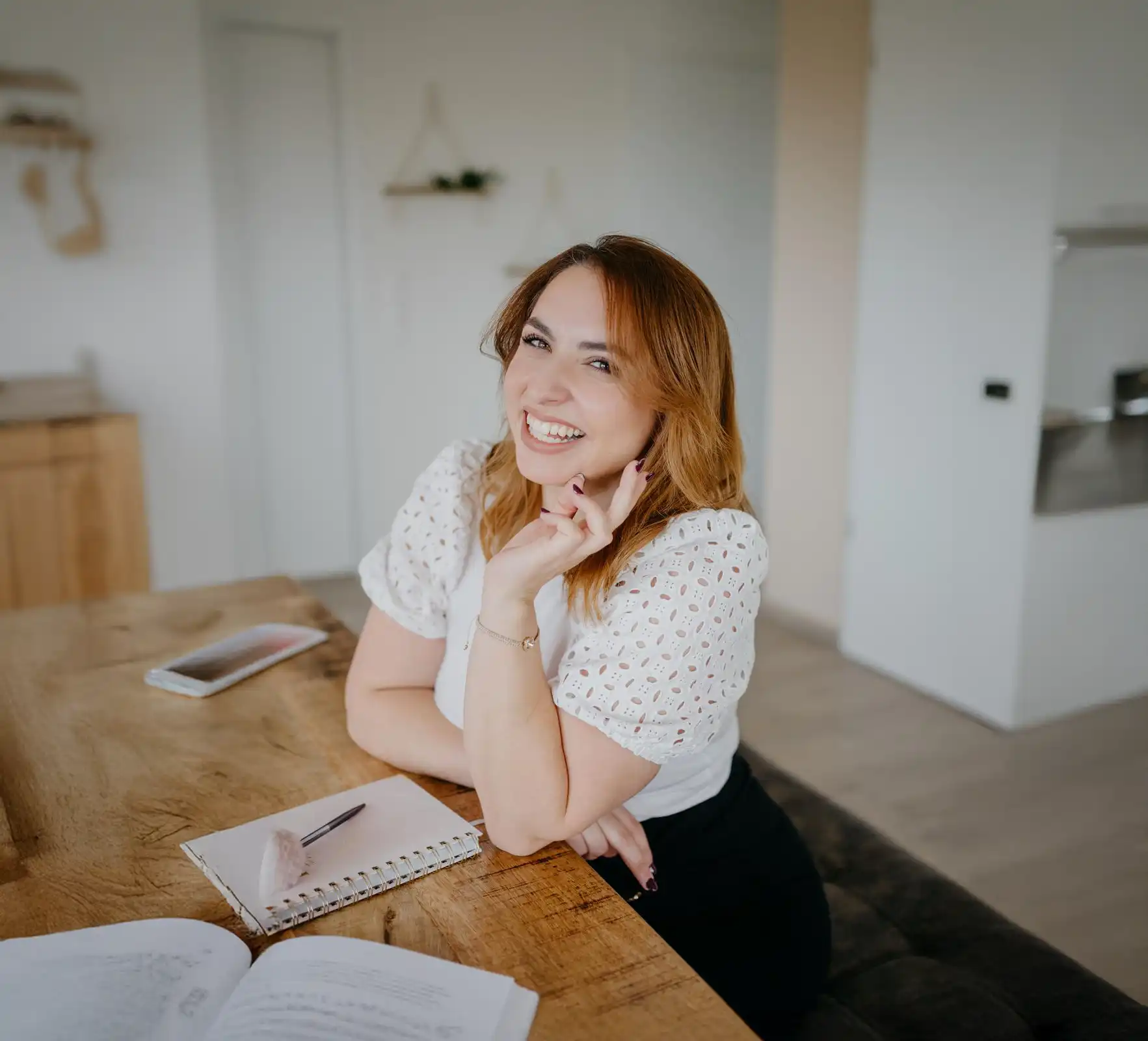 Stefania smiling at a wooden desk with a notebook and pen