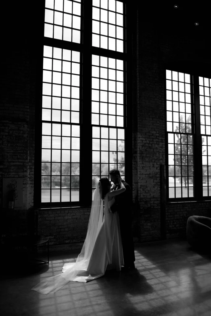Bride putting on her wedding shoes, a peaceful moment of anticipation before the big day Bride and groom in front of large loft windows sharing a quiet moment