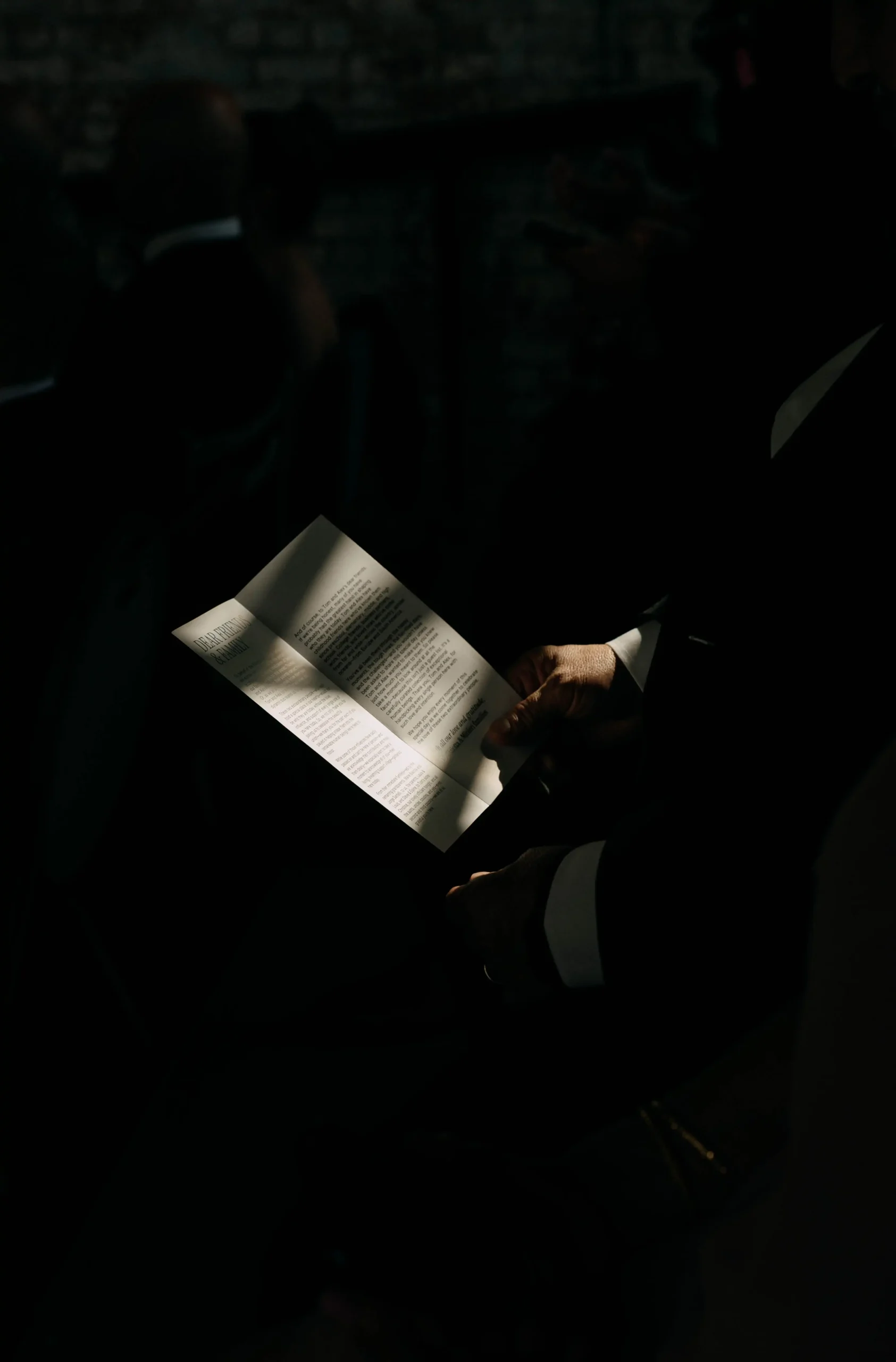 Guest reading a wedding program in low light during the ceremony