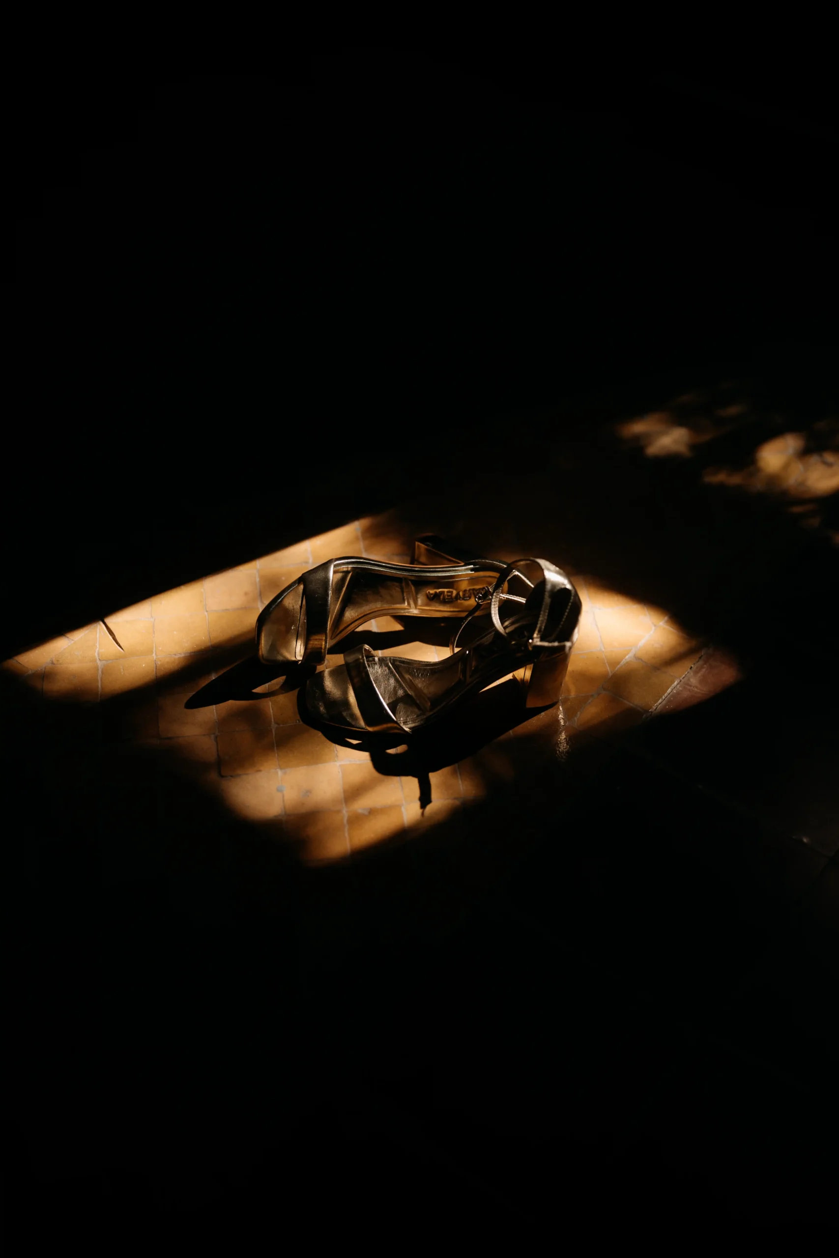 Wedding shoes in a sunlit spotlight on the floor before the ceremony.