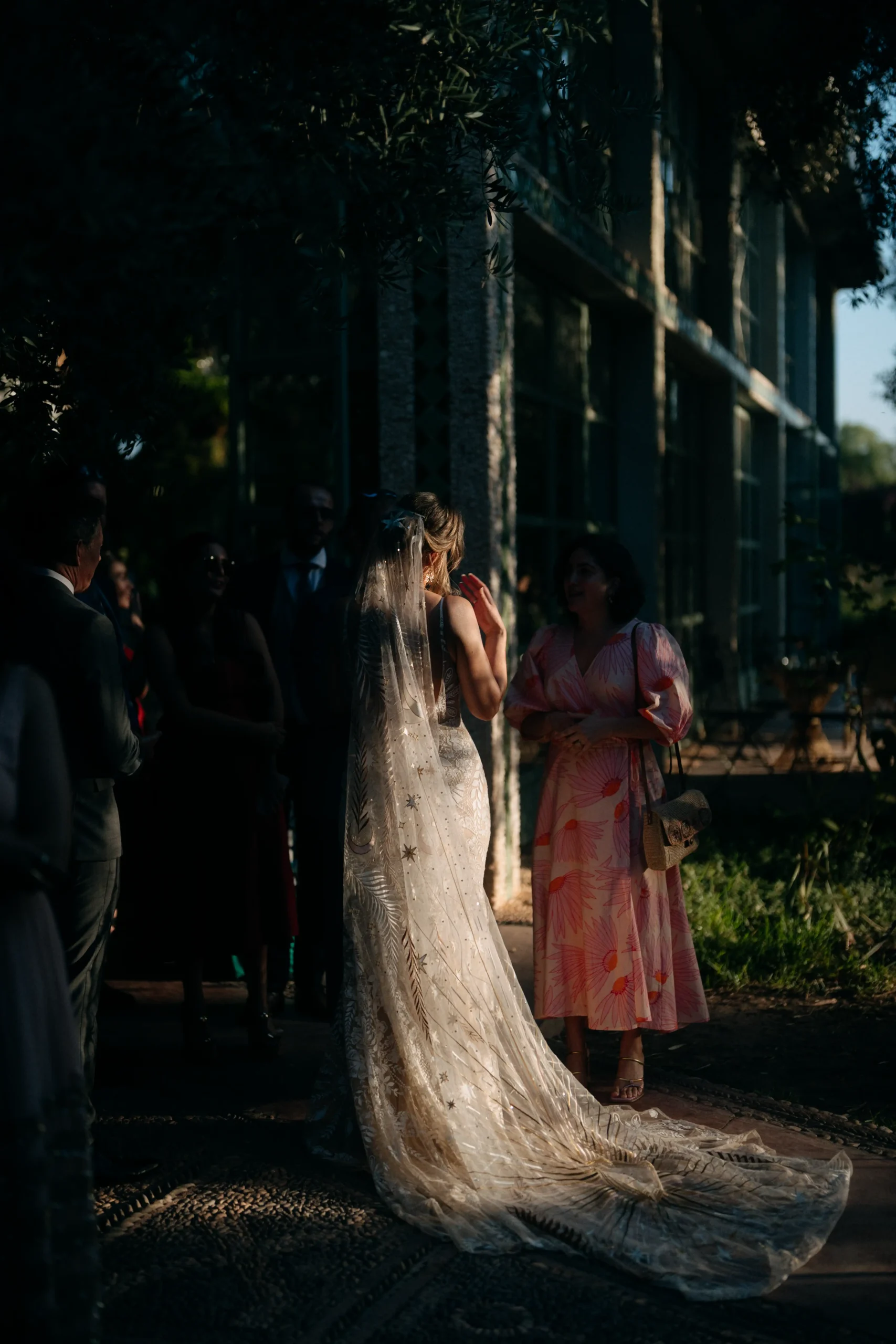 Bride in embroidered veil surrounded by guests at a golden hour wedding in Marrakech.
