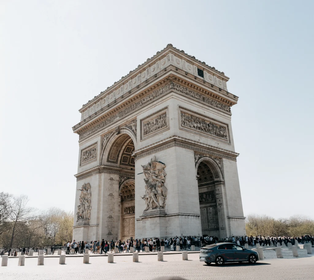 Wide-angle view of the Arc de Triomphe on a clear Paris day.
