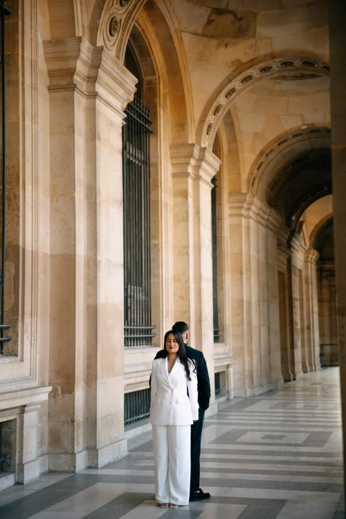 ride standing confidently in a white suit in Paris.