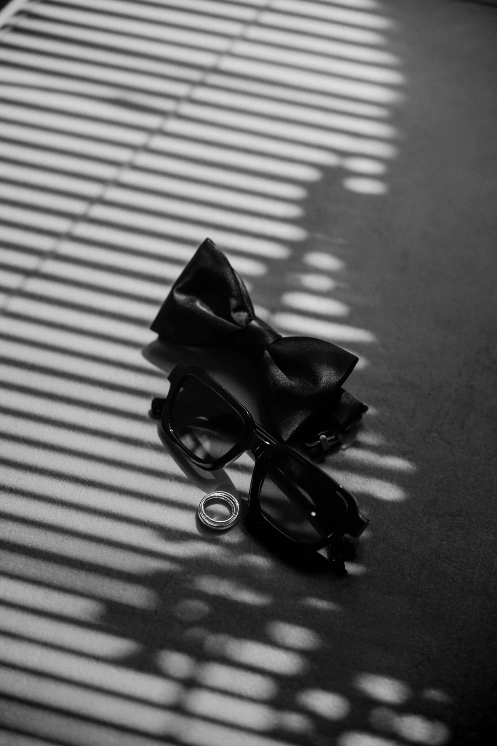 Groom’s accessories – bow tie, rings, and sunglasses in artistic shadow light