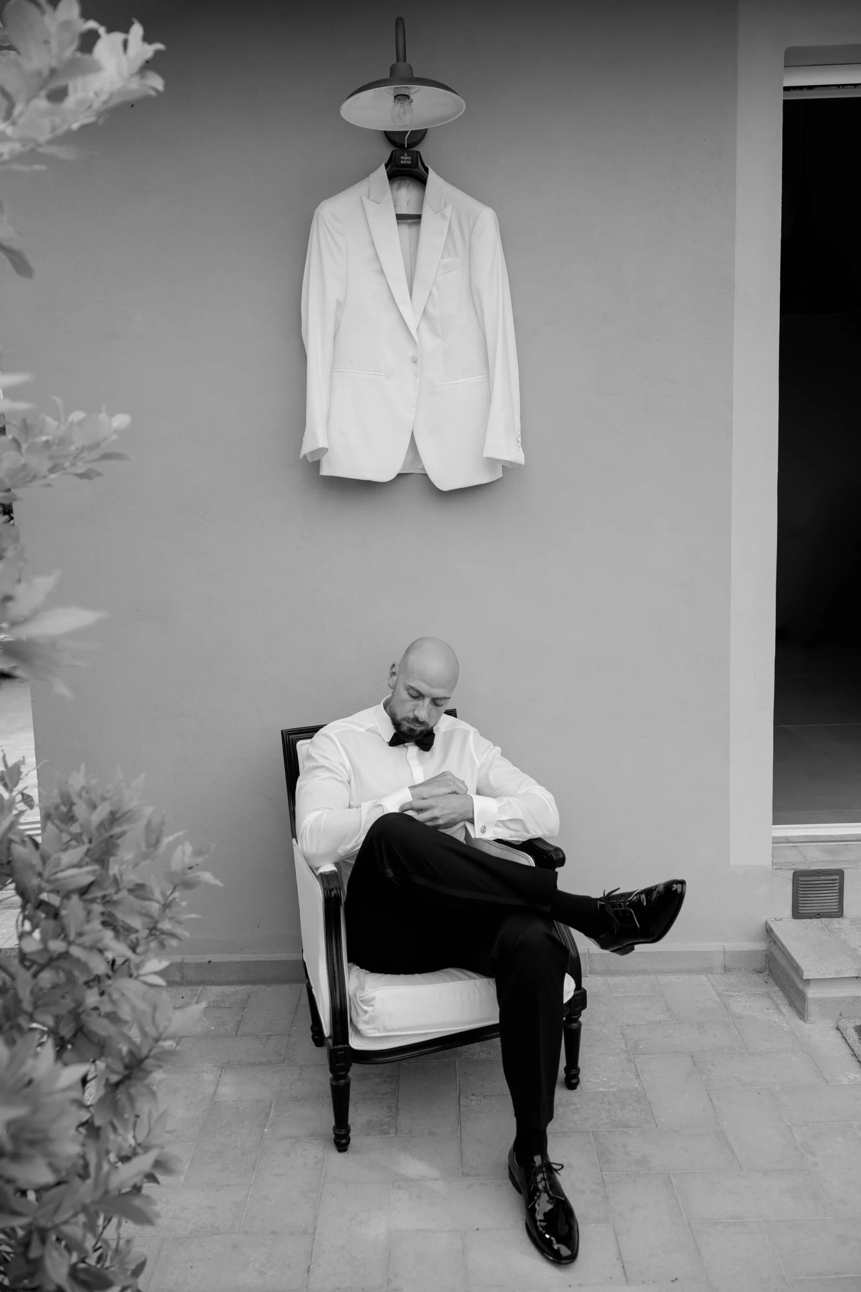 Groom sitting under his white suit before wedding in Tuscany – cinematic black and white portrait