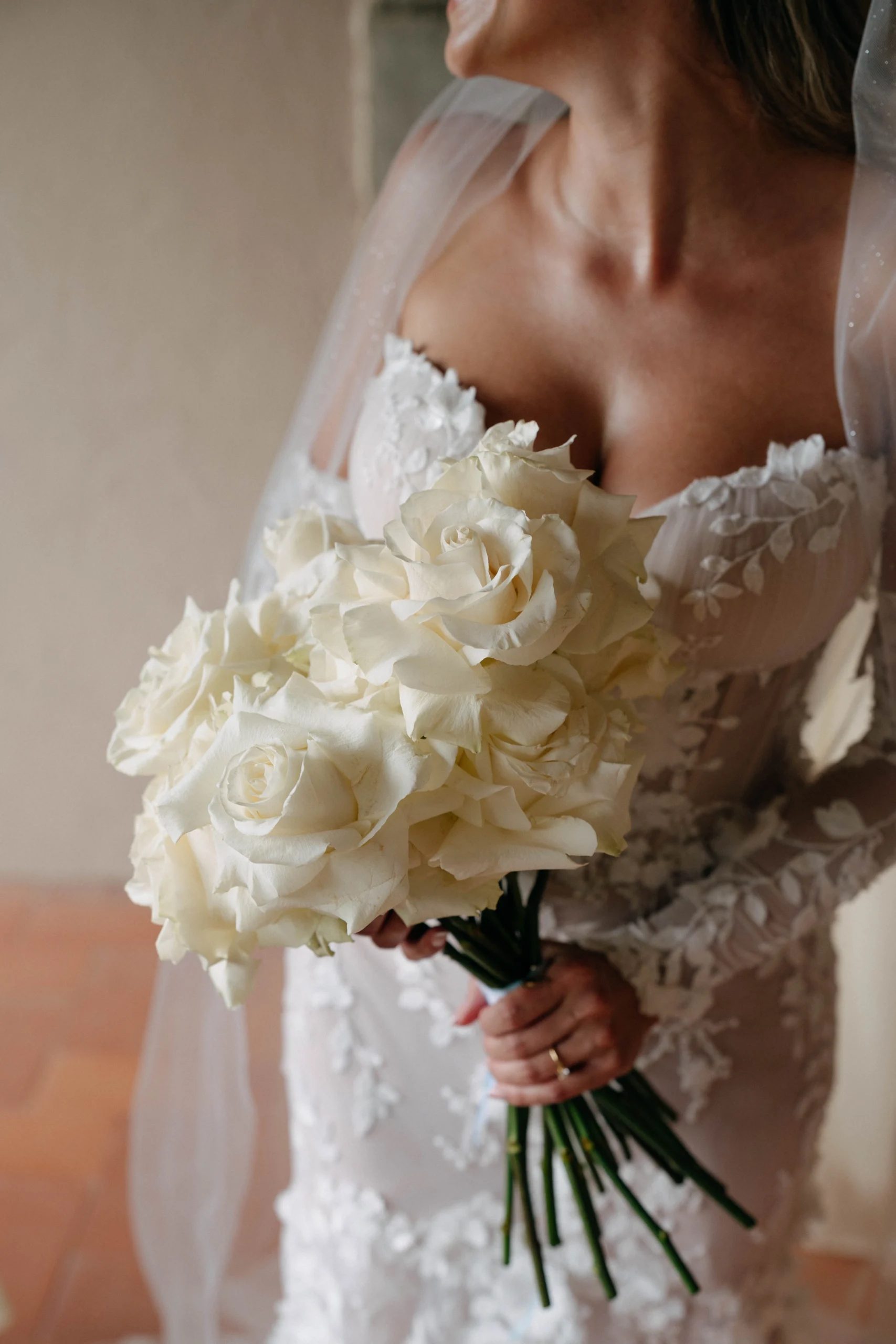 Close-up of bride holding white roses before Tuscany destination wedding – soft light, romantic detail