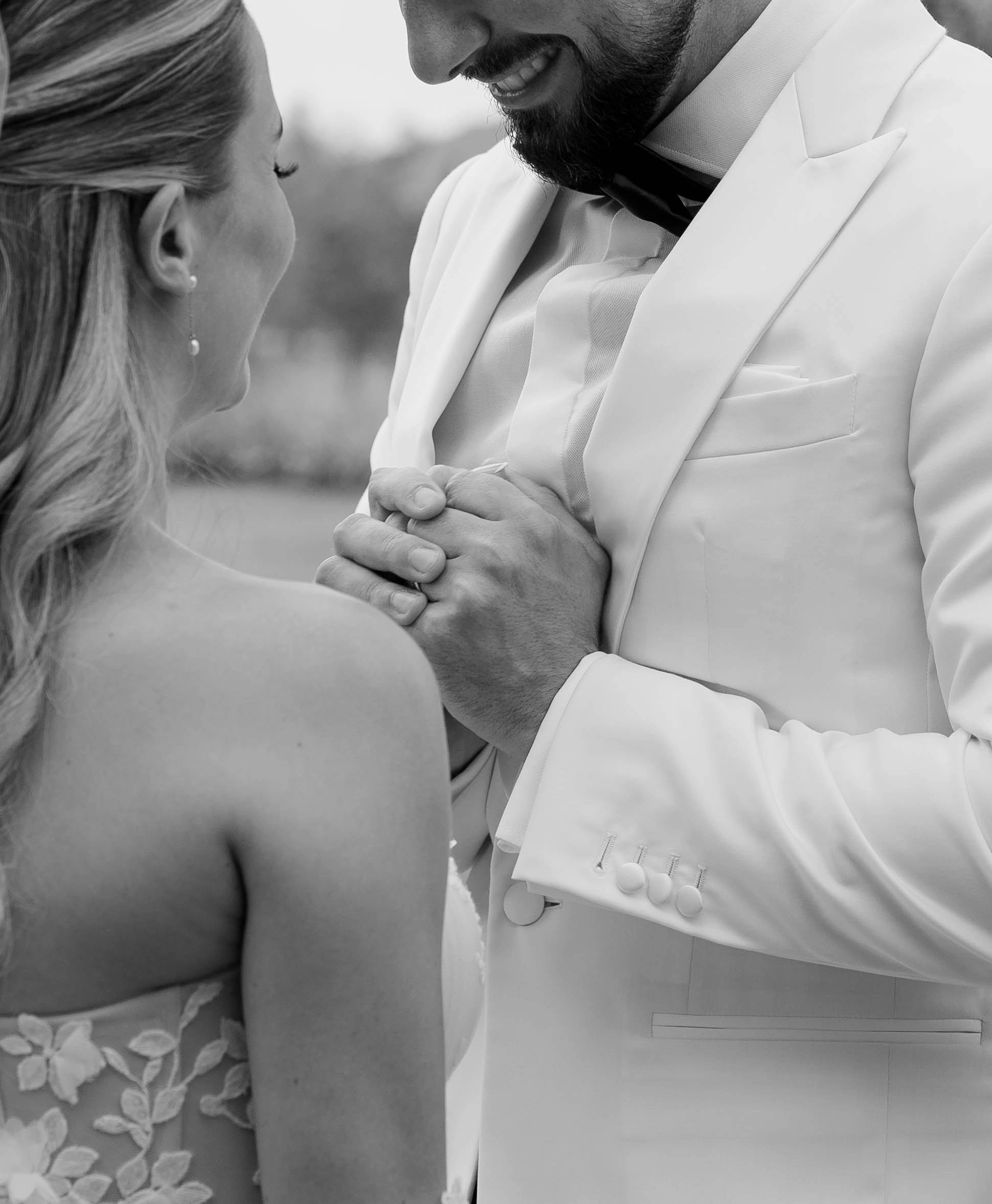 Groom holds bride’s hands during a quiet moment before the ceremony – black and white close-up