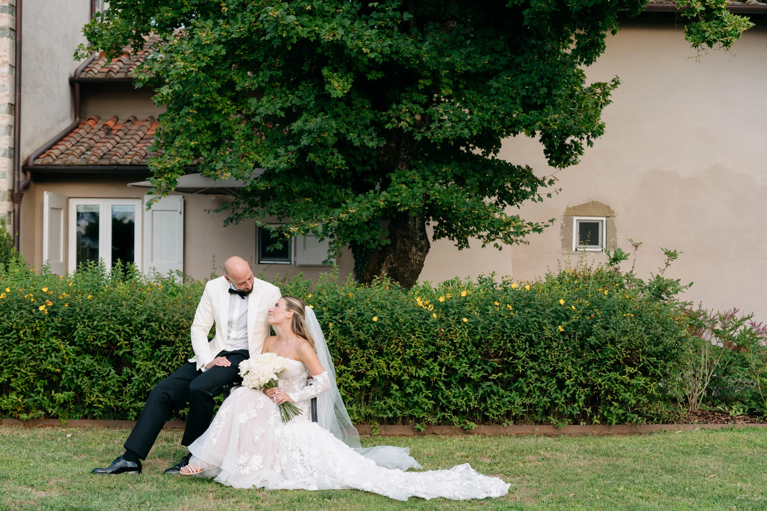 Bride and groom seated in the garden of their Tuscan venue, sharing an intimate gaze