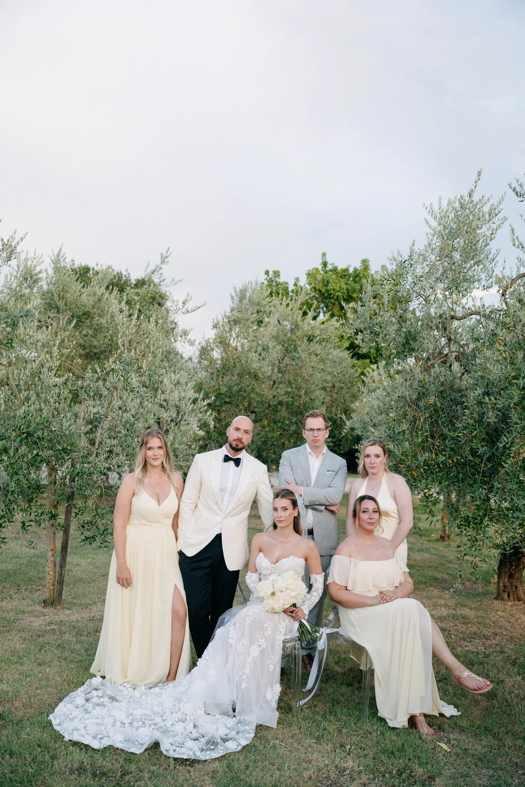 Elegant destination wedding in Tuscany 2026 with the bride and bridal party in soft yellow and ivory dresses, surrounded by olive trees.
