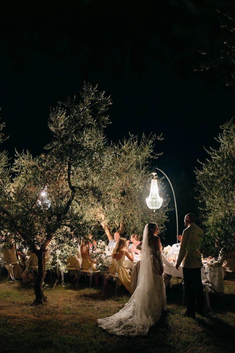 Bride and groom standing together under chandeliers during nighttime
