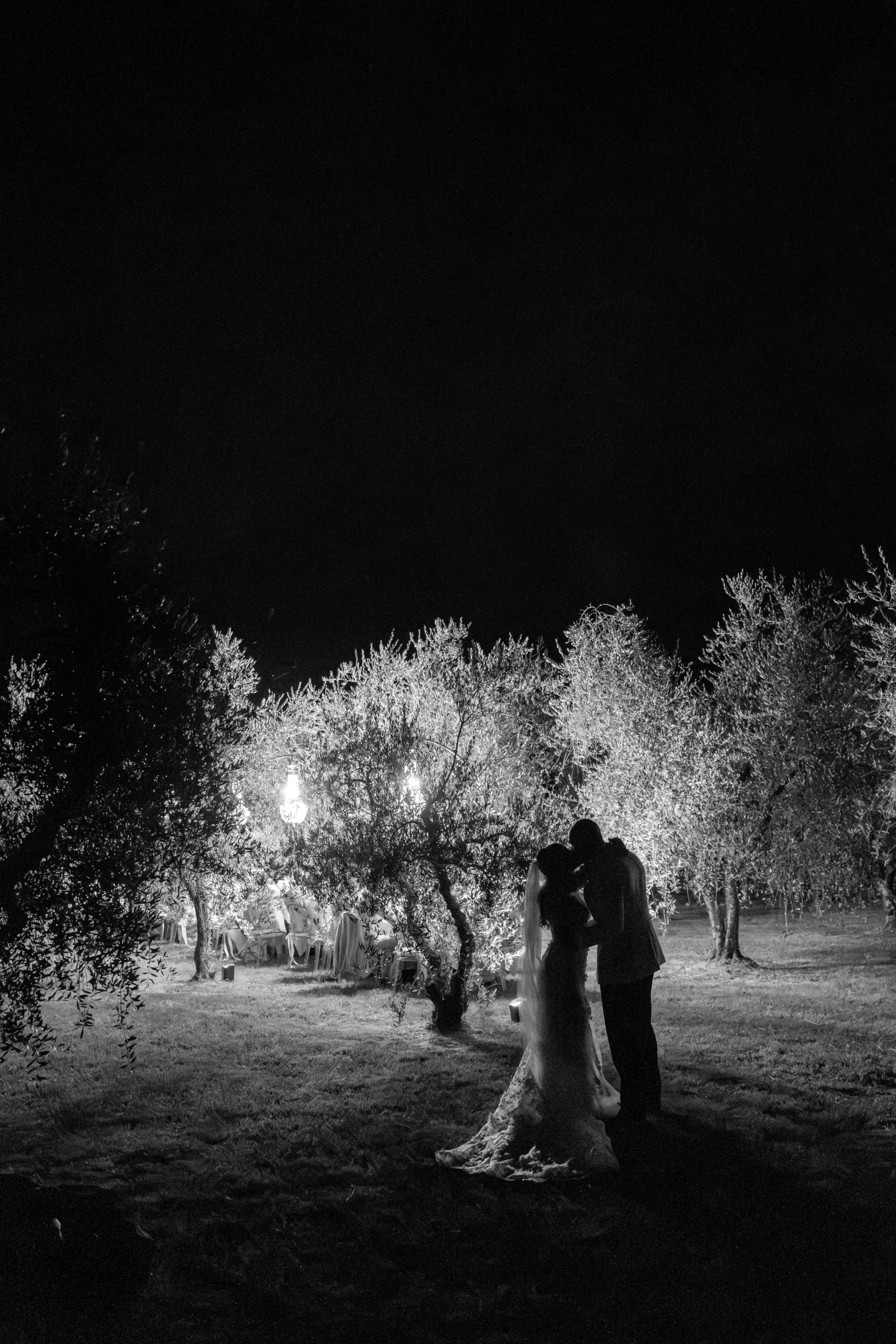 Bride and groom standing together outdoor dinner celebration in olive grove, Tuscany wedding
