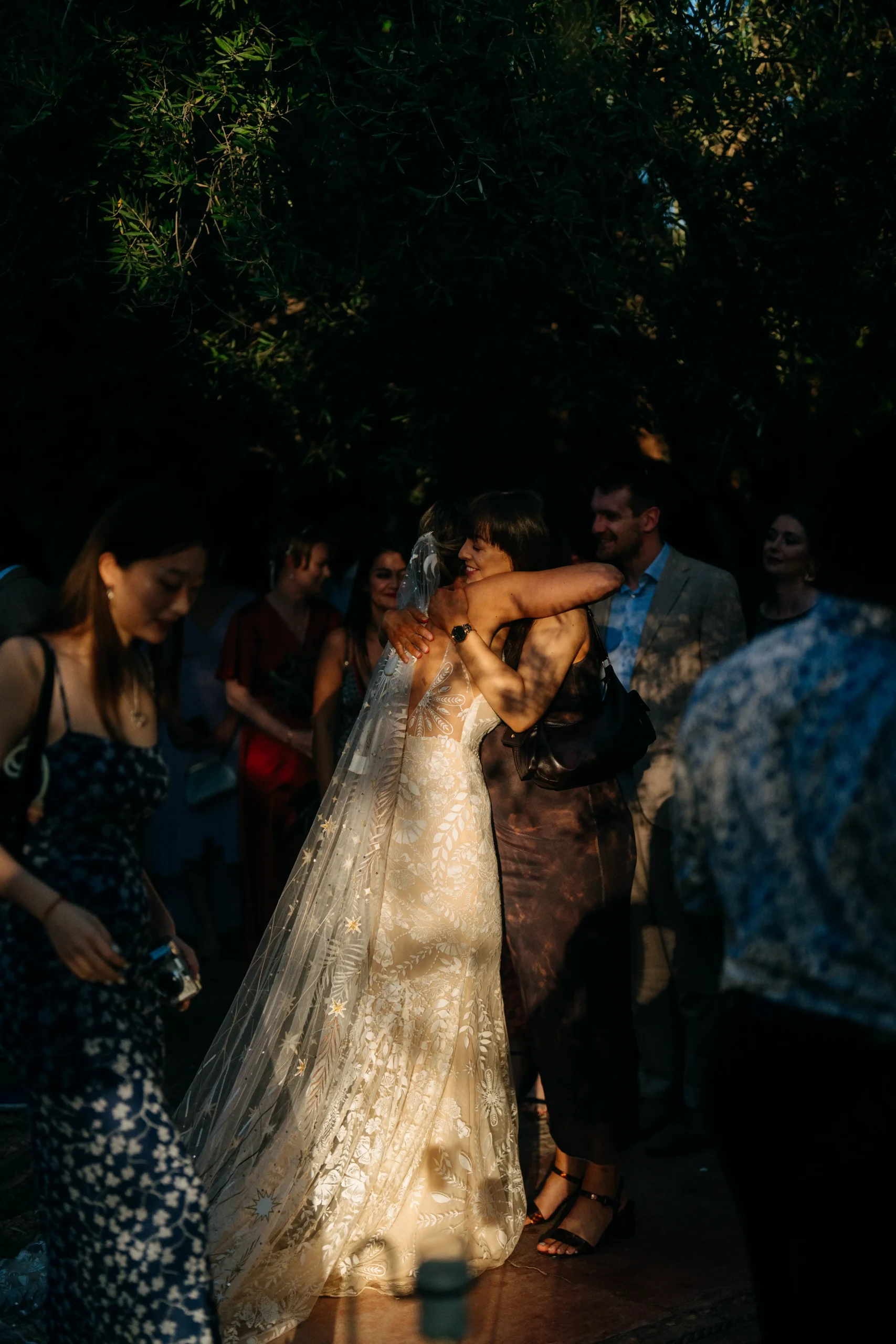 Bride in embroidered veil hugs guest during golden hour at Marrakech wedding