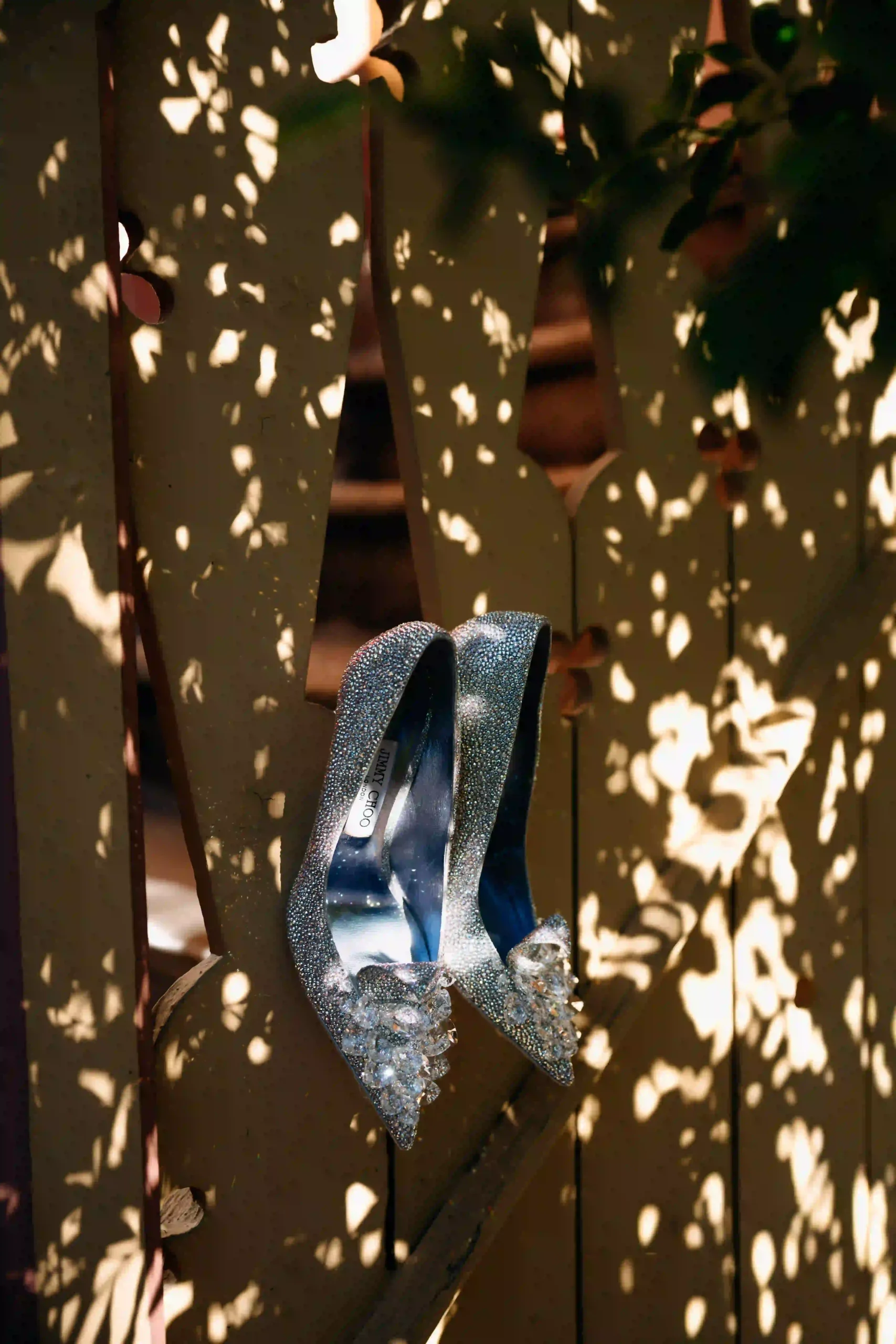 Sparkling bridal shoes on a ladder in dappled leaf light, Munich wedding at La Villa