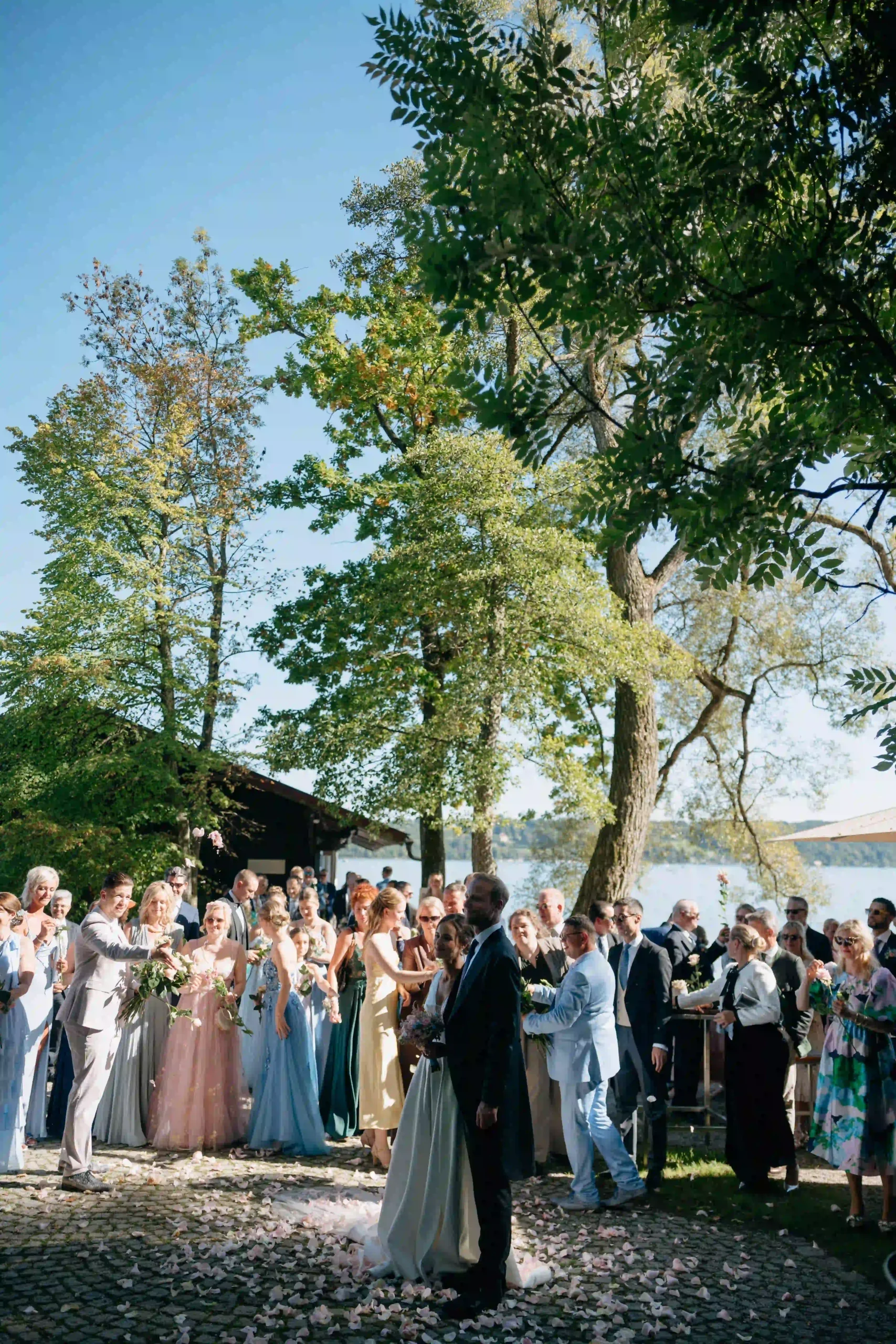 Couple outdoors in front of guests under trees, sunny moment, Munich wedding at La Villa