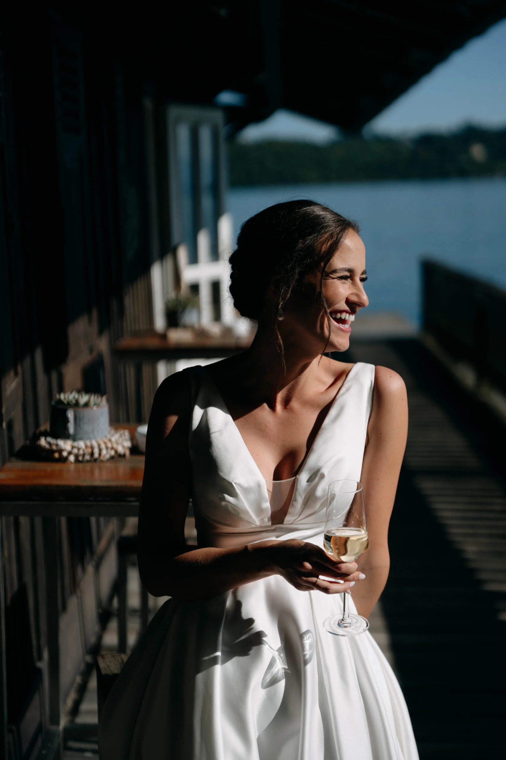 Bride laughing in sunlight on the pier holding a glass, Munich wedding at La Villa