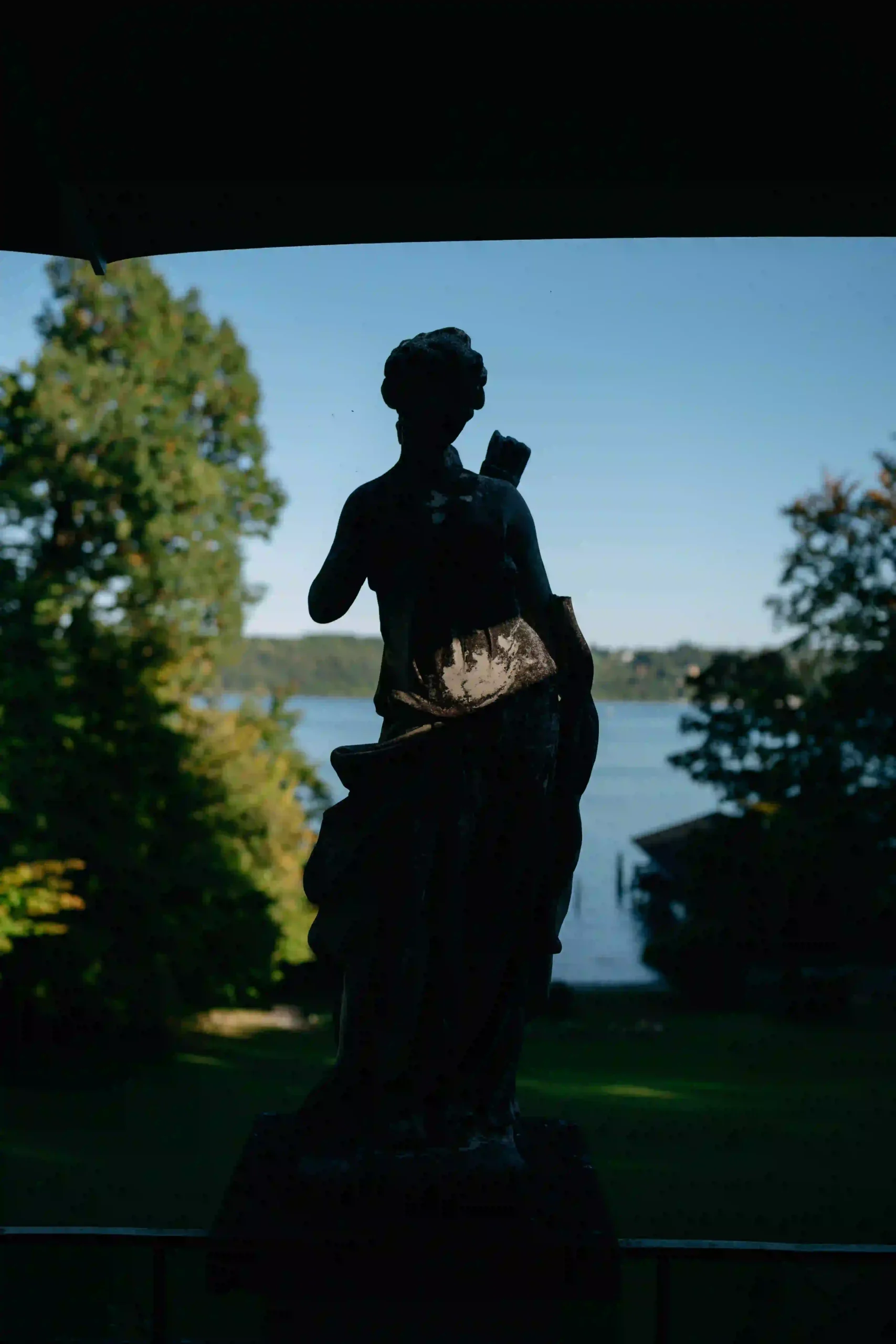 Statue silhouette against blue sky and lake, wedding story in Munich at La Villa