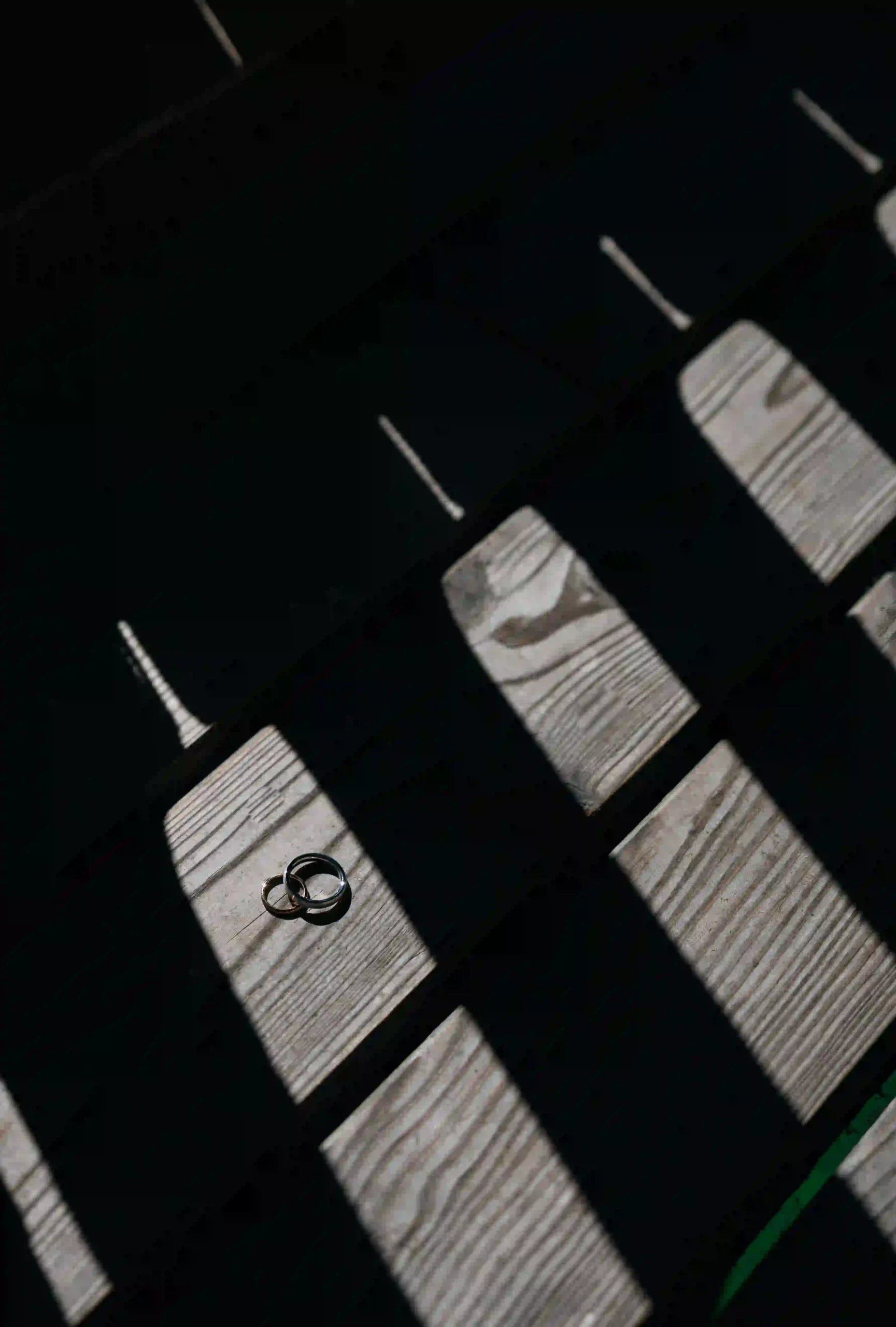 Wedding rings on a bench in patterned shadows, Munich wedding at La Villa