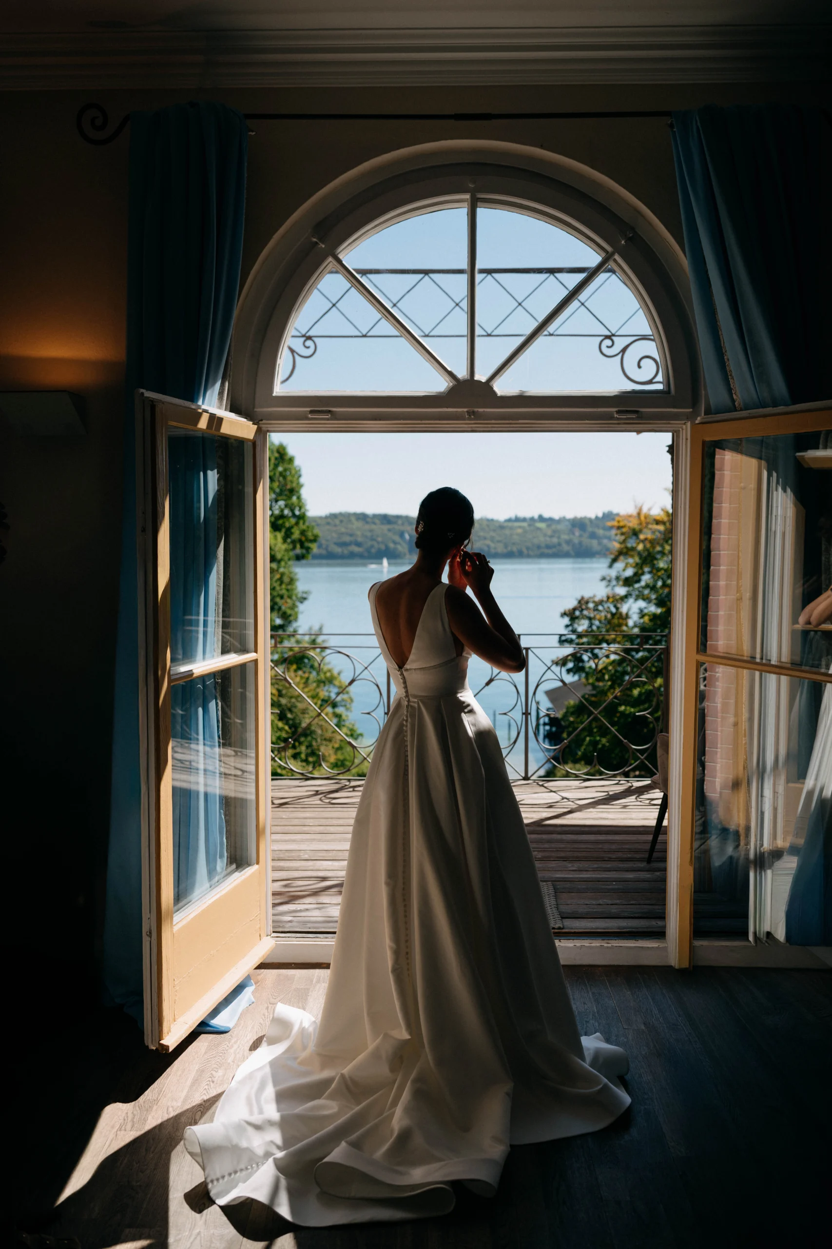  Bride in her dress framed by open doors with a lake view, Munich wedding at La Villa