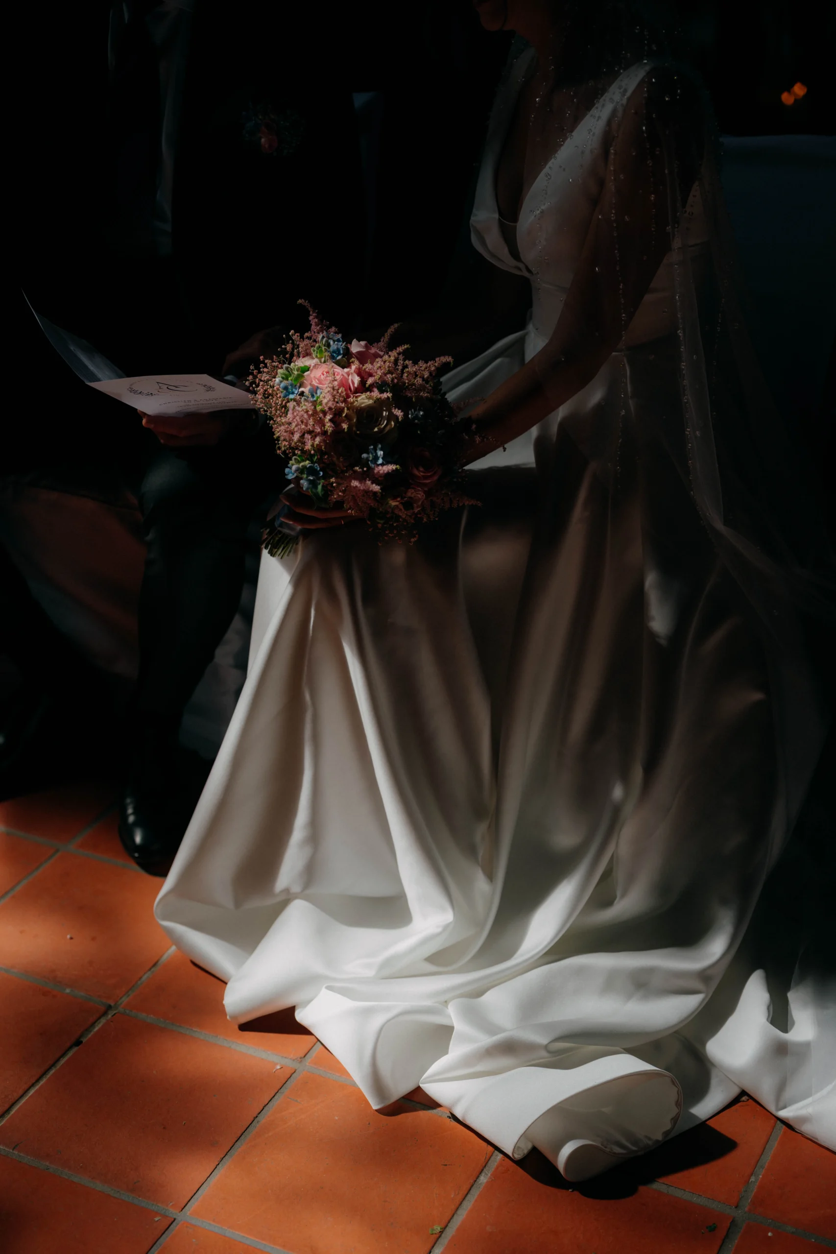 Bride’s dress on terracotta tiles with bouquet in shadowed light, Munich wedding at La Villa