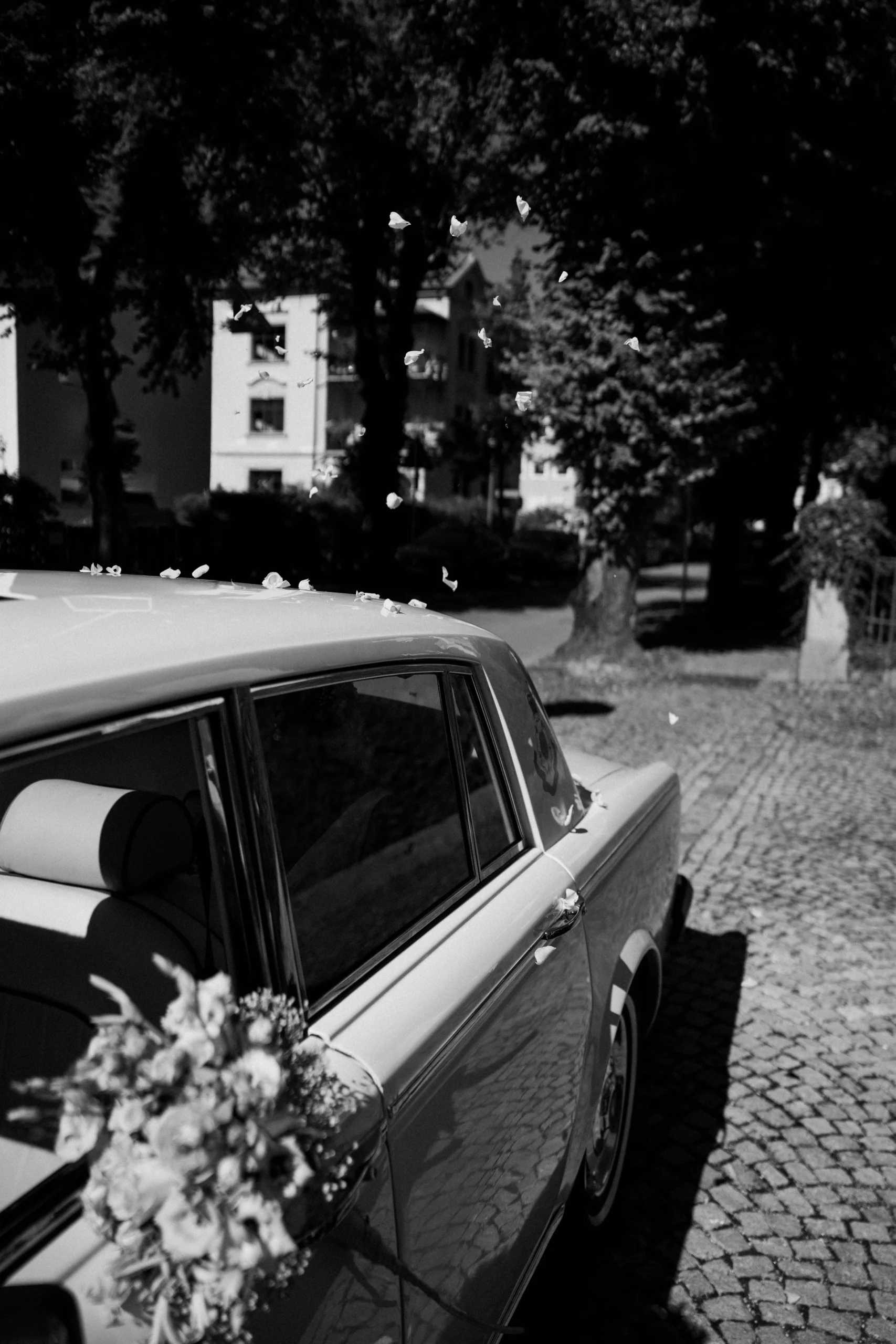 Vintage car with flowers on cobblestones, black and white, Munich wedding at La Villa