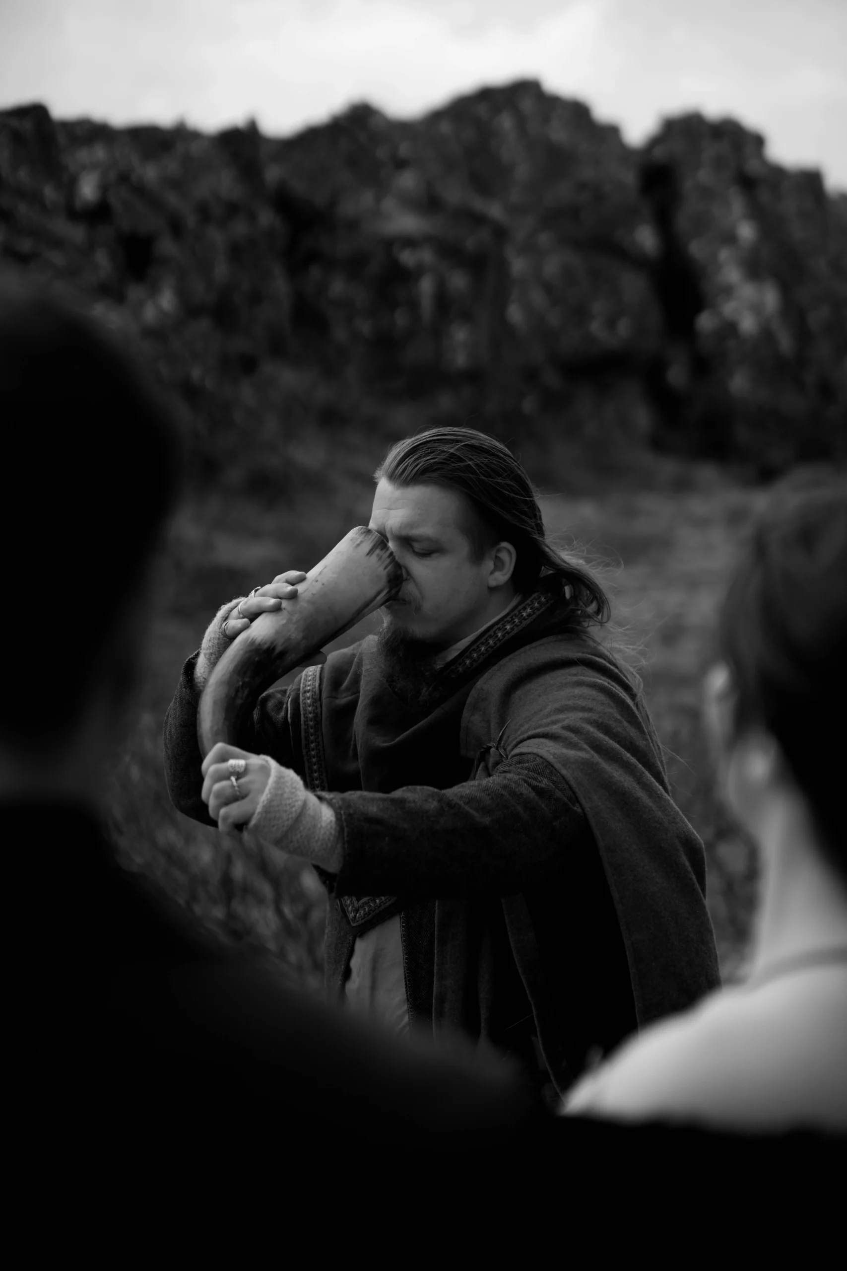 Black-and-white photo of man blowing a drinking horn during ceremony in Iceland