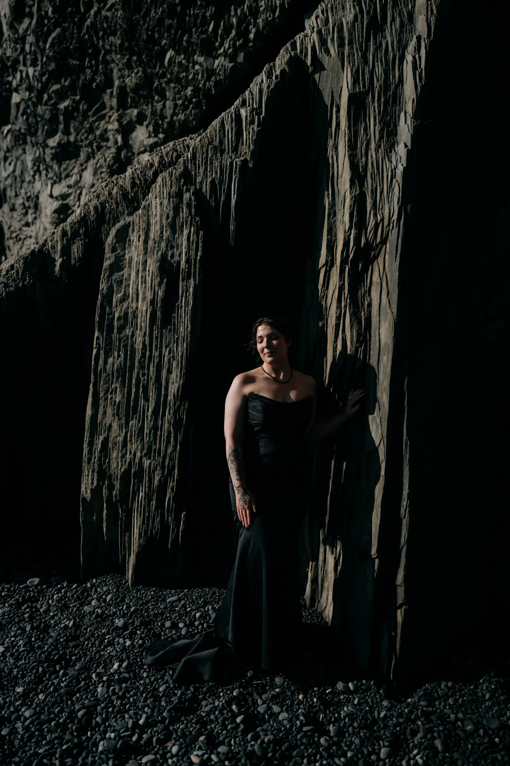 Bride in black gown posing in textured lava cave in Iceland