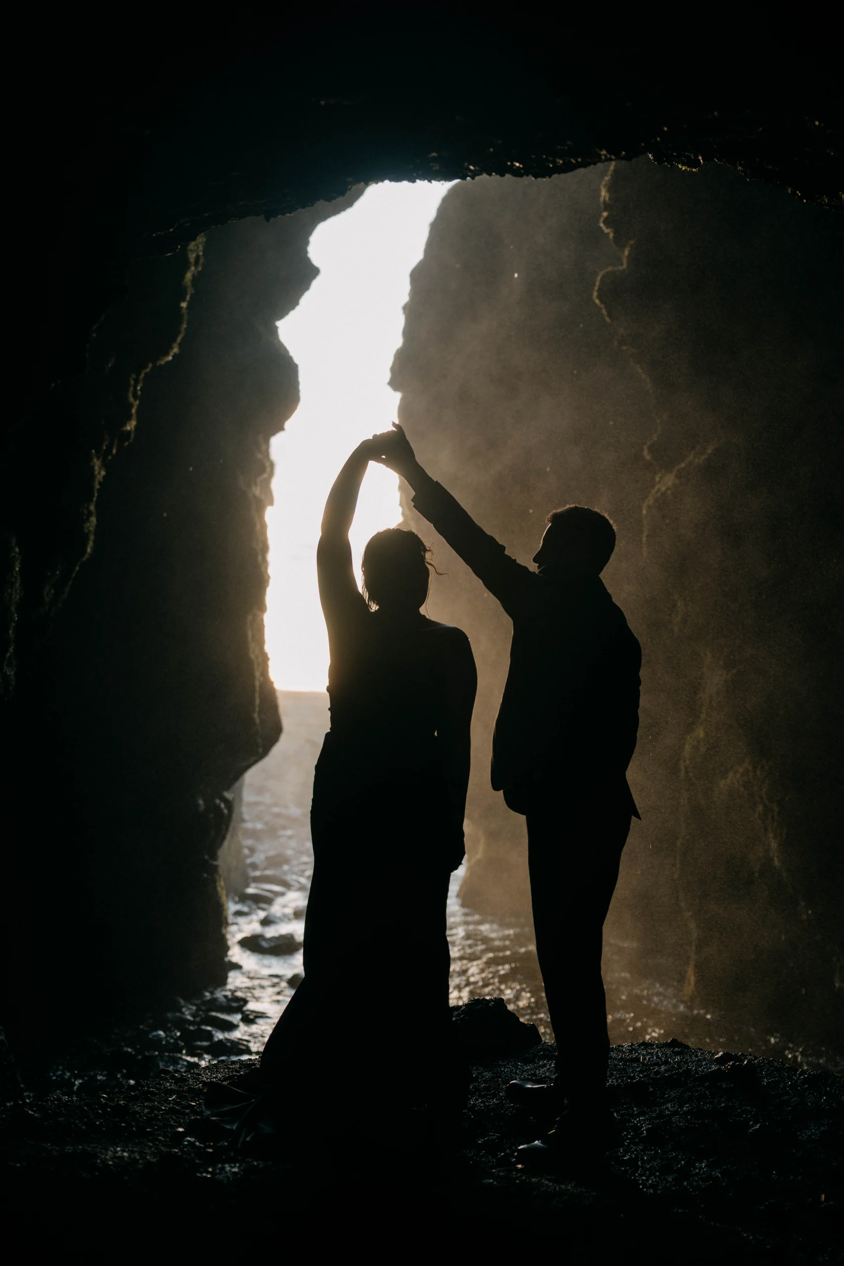 Couple exchanging rings while kneeling in rocky alcove, Iceland