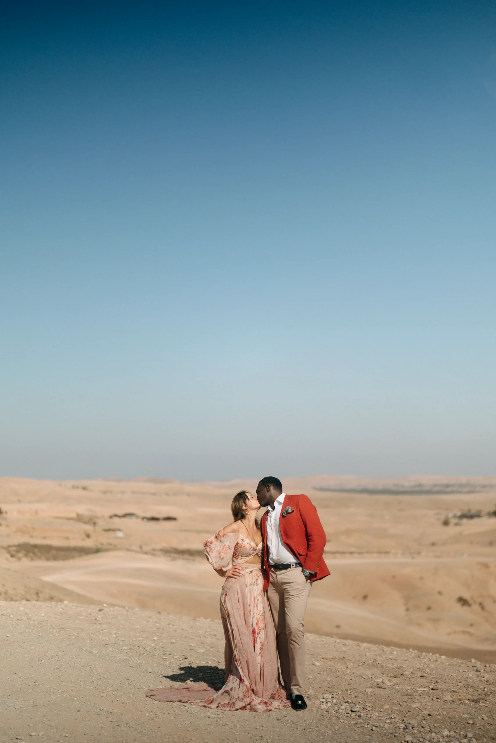 Couple kissing above the Agafay Desert hills near Marrakech on the final day of their wedding